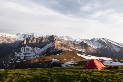 冰封山旁草地上的红色帐篷自然摄影